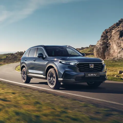 Hybrydowy SUV CR-V jadący drogą w górzystym terenie.